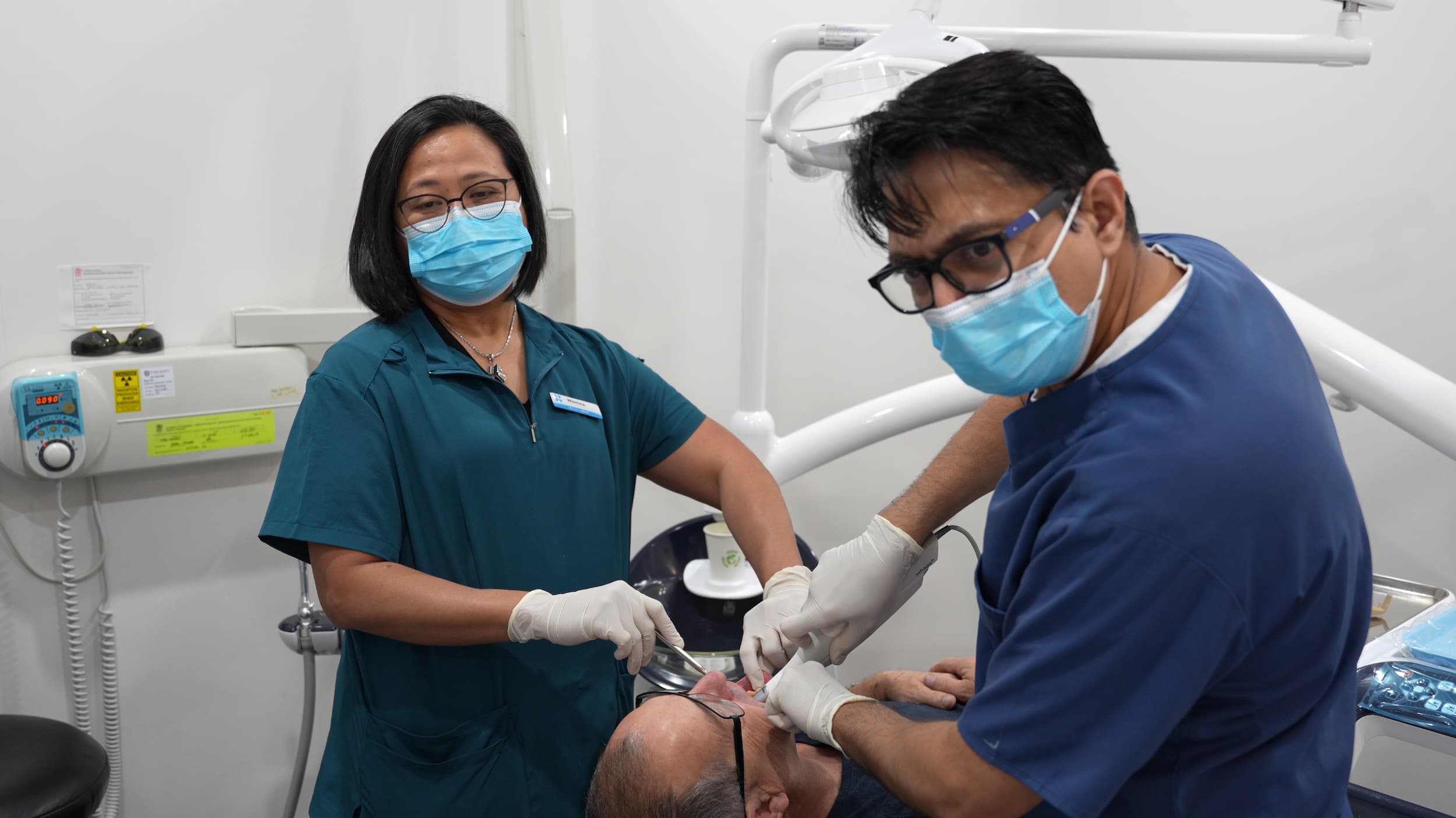 Dr Rajeev Bhandare and Wilmina assisting a patient during a dental procedure