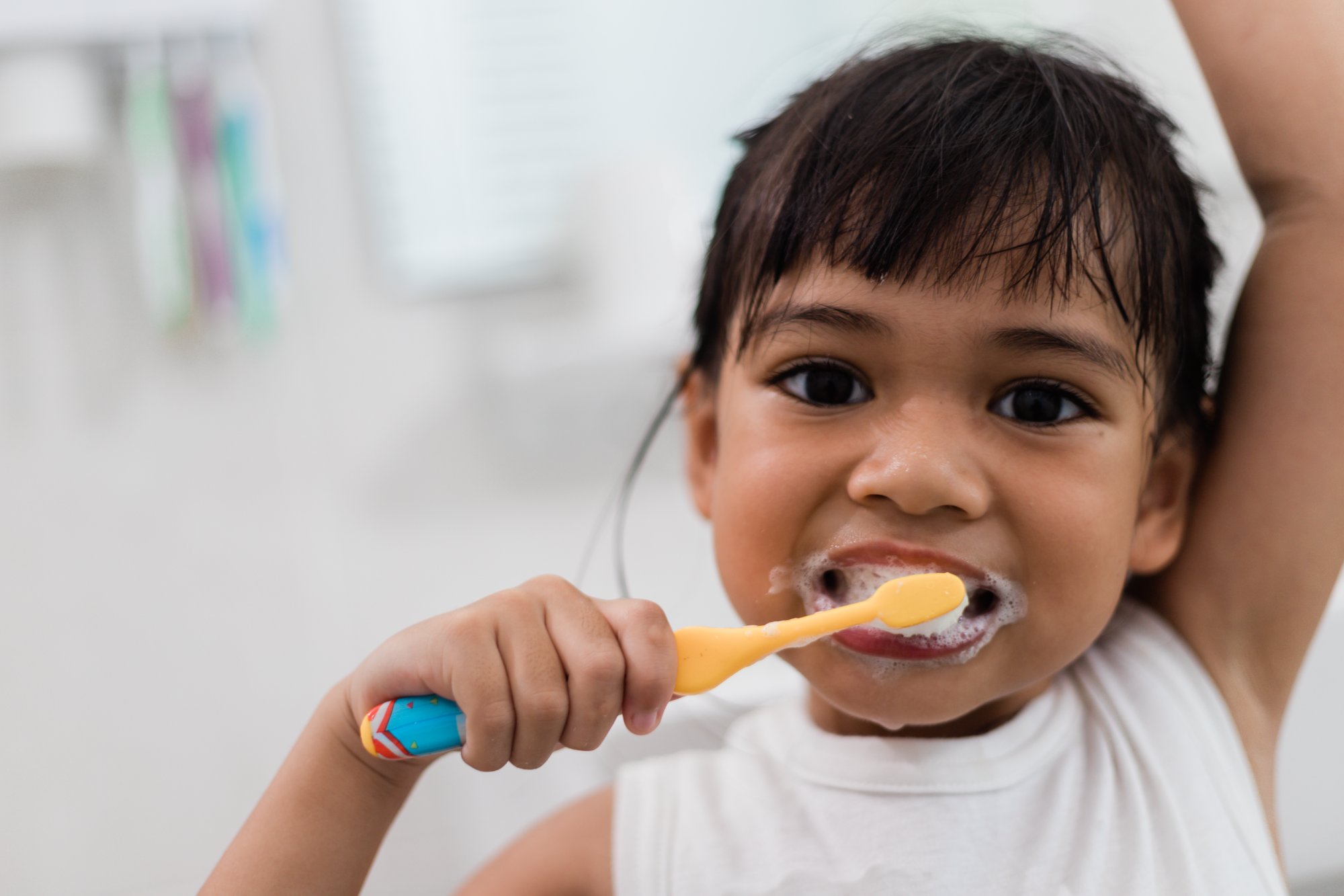 Child brushing teeth with yellow toothbrush