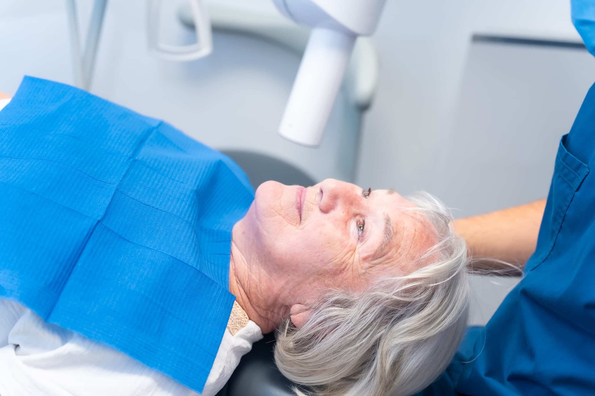 Elderly patient receiving All-On-X dental implant consultation at Exquisite Smiles