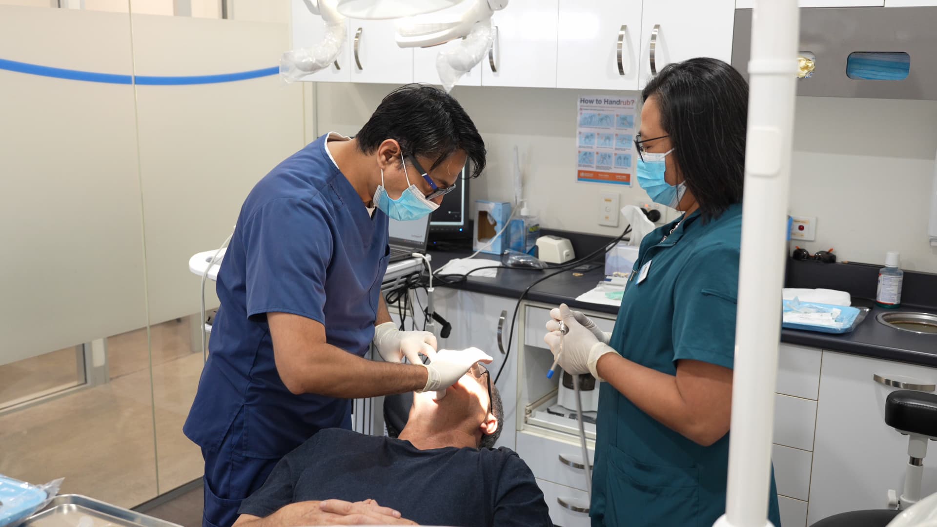 Dentist providing general dentistry treatment with dental assistant at Exquisite Smiles