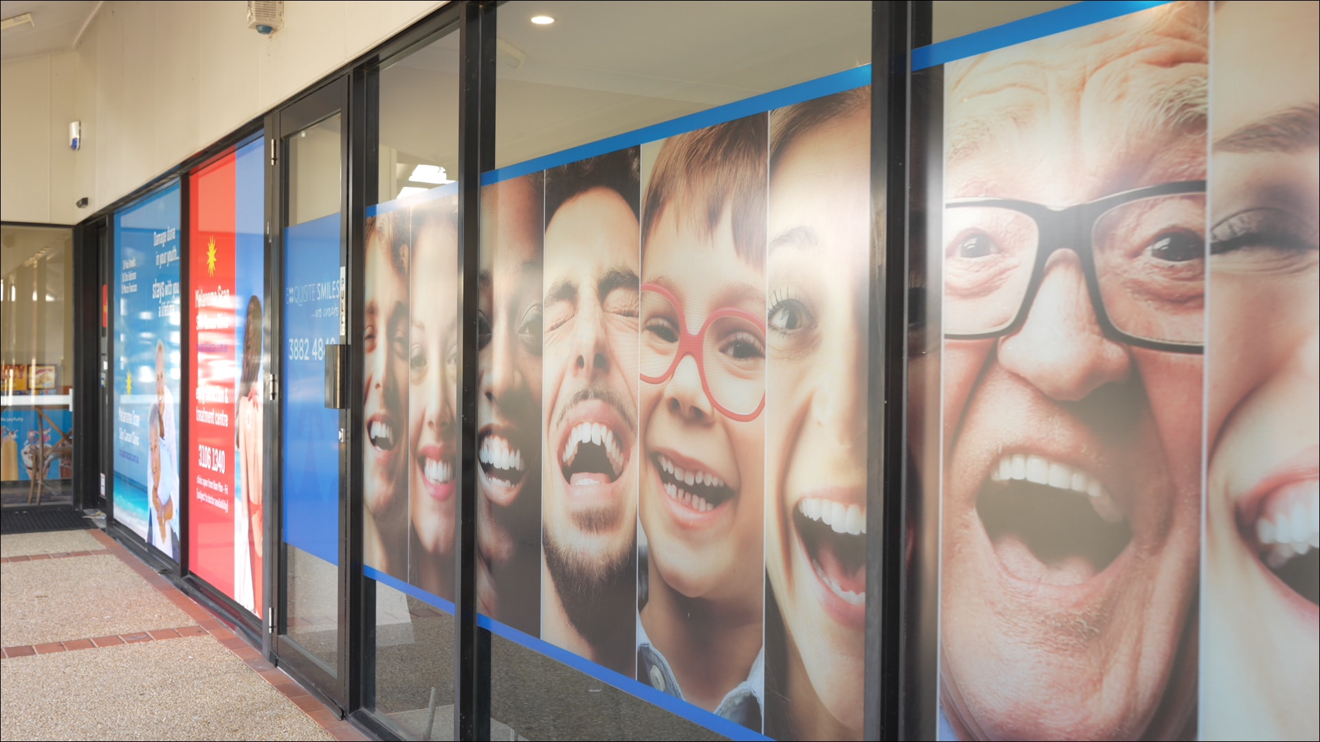 Exquisite Smiles clinic window signage showing smiling patients outside the practice.